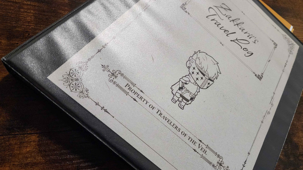Black binder on wood table. Binder has a sheet of off-white paper inside with fancy text, borders, and line art version of Zakkarii's pngtuber. The text says: Zakkarii's Travel Log. Property of Travelers of the Veil.
